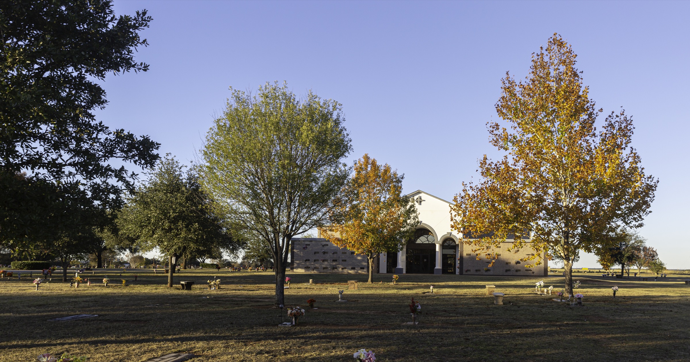 Autumn trees and the mausoleum across the lawn at Holly Hills Memorial Park